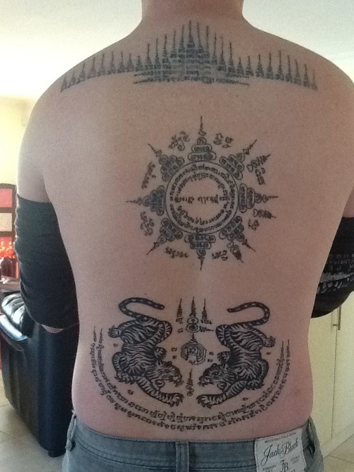 A Lanna-tradition Sak Yant master hand-poking a sacred Yant tattoo on a respectful foreign client in a Chiang Mai studio